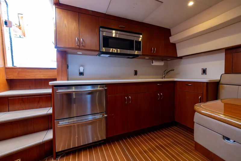 Slide: The Image of Luxurious 2012 Cabo 44 Hardtop Express yacht kitchen with wood cabinetry and modern appliances. - 88