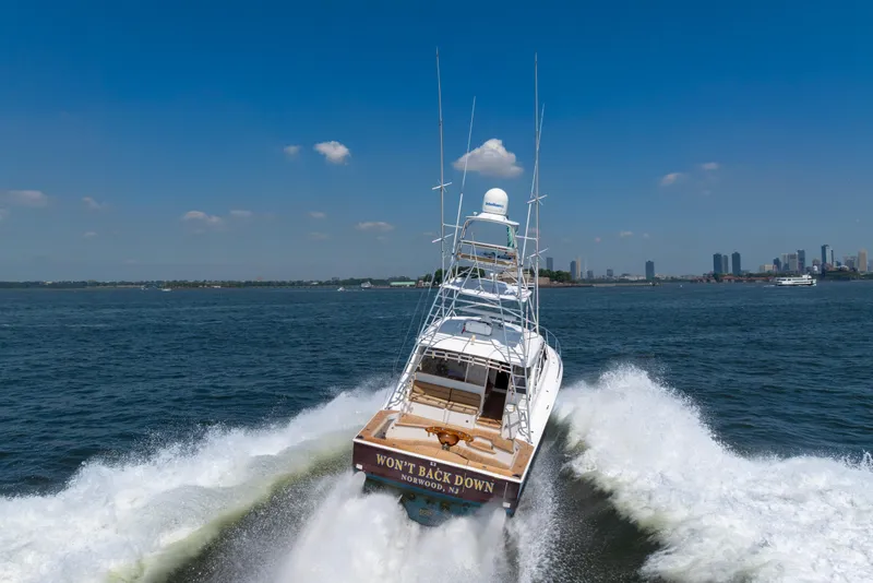 Slide: The Image of 2012 Cabo 44 Hardtop Express yacht cruising on open water, city skyline in background. - 9