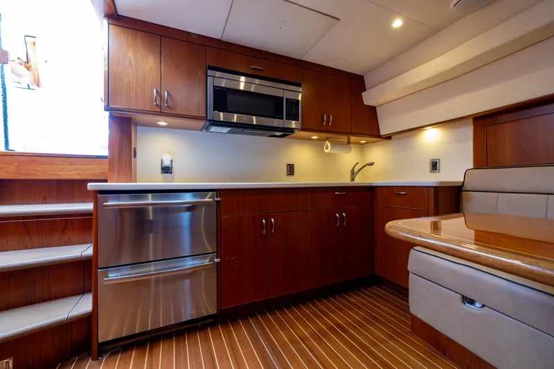 Slide: The Image of 2012 Cabo 44 Hardtop Express yacht kitchen with wood cabinets, microwave, and sink. - 90