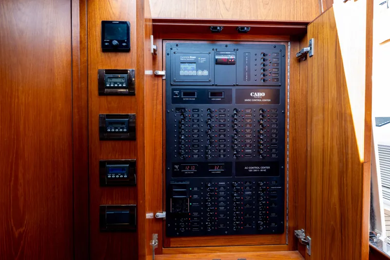 Slide: The Image of Electrical control panel inside 2012 Cabo 44 Hardtop Express yacht, featuring wooden cabinetry. - 94