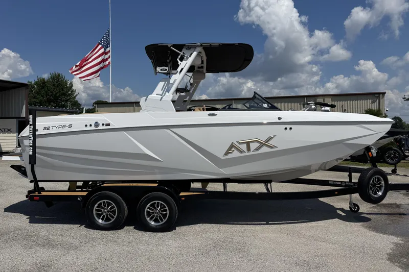 Slide: The Image of 2026 ATX Surf Boats 22 Type-S on trailer, American flag in background, sunny day. - 2