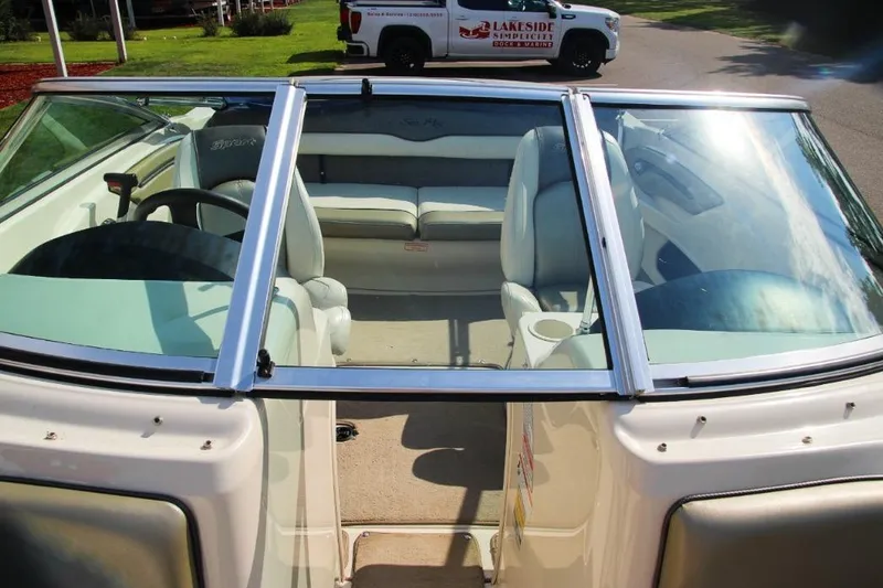 Slide: The Image of 2006 Sea Ray 205 Sport boat interior with seating and steering wheel, parked outdoors. - 6