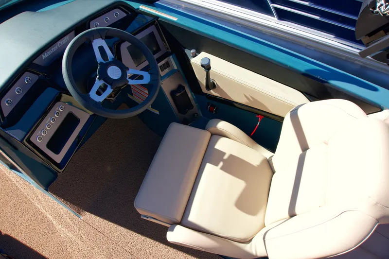 Slide: The Image of 2025 MasterCraft NXT20 boat interior with steering wheel and beige seating. - 10