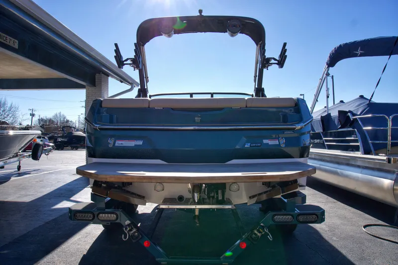 Slide: The Image of 2025 MasterCraft NXT20 boat, rear view, parked outdoors under clear blue sky. - 3