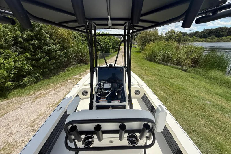 Slide: The Image of 2026 Pathfinder 2300 HPS boat interior with steering console, docked near lush greenery. - 14