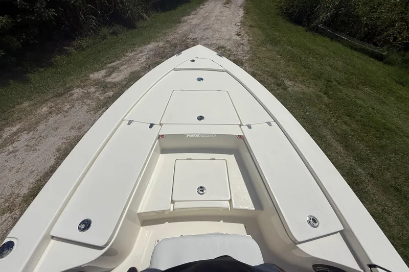 Slide: The Image of 2026 Pathfinder 2300 HPS boat deck, white with storage compartments, on grassy path. - 17