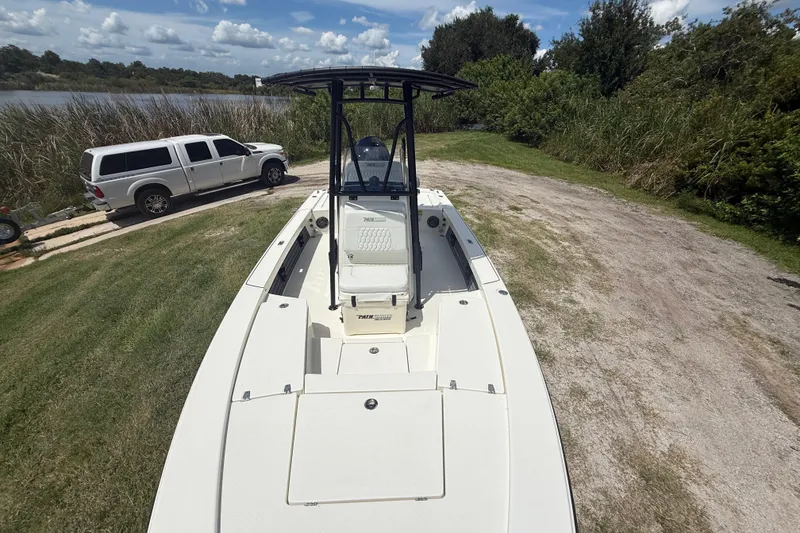 Slide: The Image of 2026 Pathfinder 2300 HPS boat on grassy shore near a parked truck. - 19