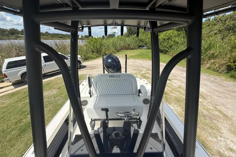 Slide: The Image of 2026 Pathfinder 2300 HPS boat interior with console and seating, parked near a lake. - 21