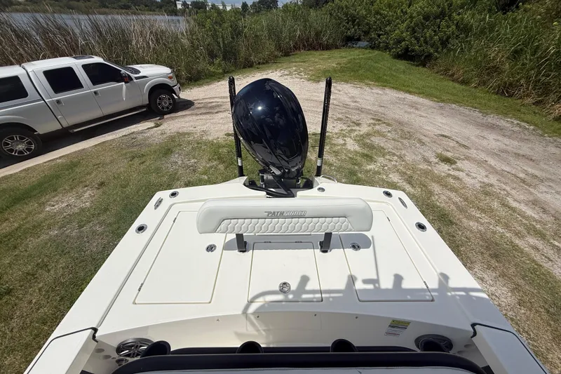 Slide: The Image of 2026 Pathfinder 2300 HPS boat with motor, parked near a white truck by a lake. - 22