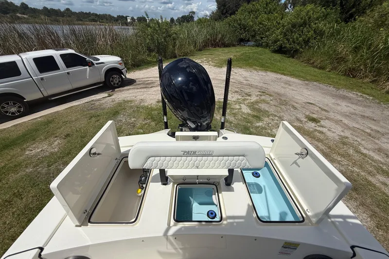 Slide: The Image of 2026 Pathfinder 2300 HPS boat with open compartments, parked near a lake and truck. - 23