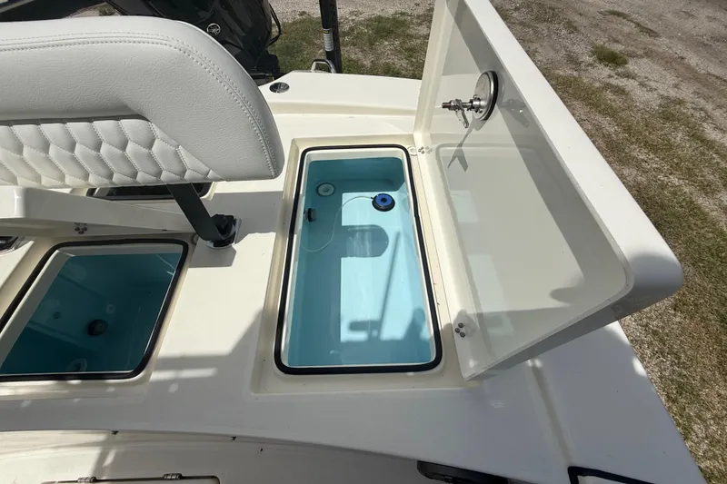 Slide: The Image of 2026 Pathfinder 2300 HPS boat with open storage compartment and white cushioned seat. - 26