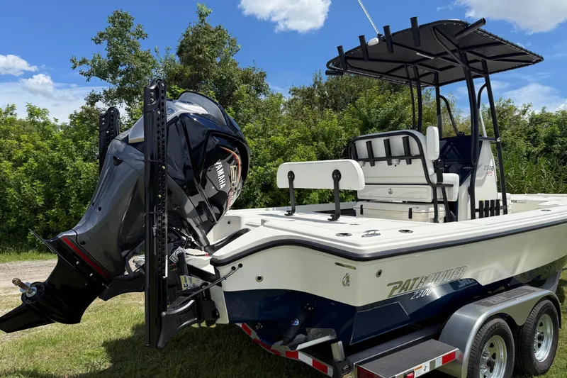 Slide: The Image of 2026 Pathfinder 2300 HPS boat with Yamaha engine, parked on a trailer, surrounded by greenery. - 5