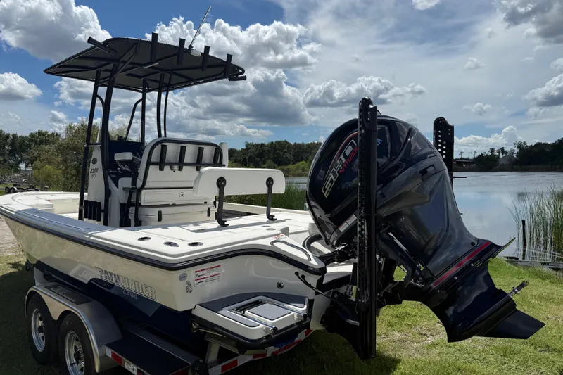 Slide: The Image of 2026 Pathfinder 2300 HPS boat with powerful engine, parked near a serene lake. - 6