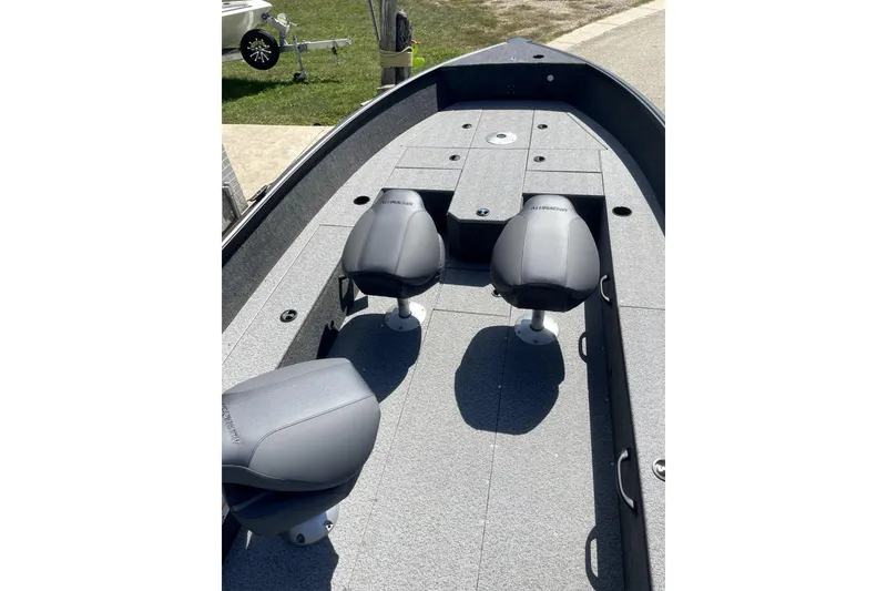 Slide: The Image of 2026 Alumacraft Voyageur 175 Tiller boat on trailer, parked outside dealership. - 2