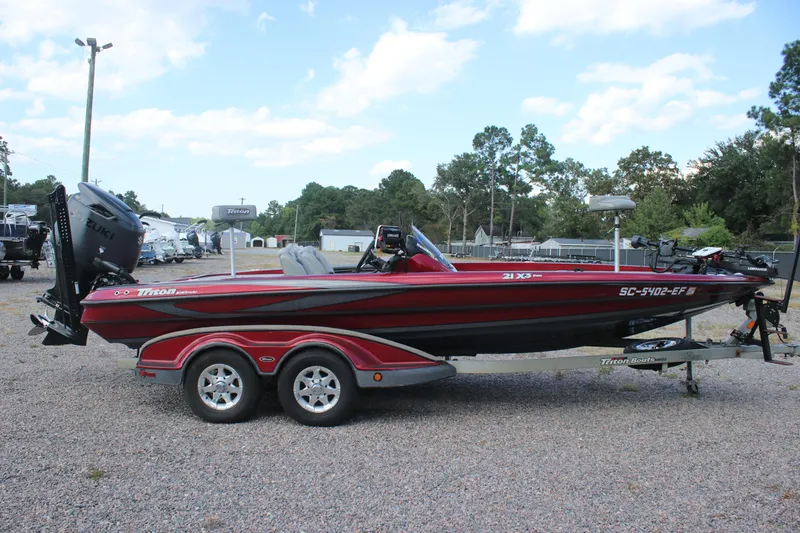 Slide: The Image of 2009 Triton 21X3 Pro DC boat on trailer, red and black design, parked outdoors. - 23