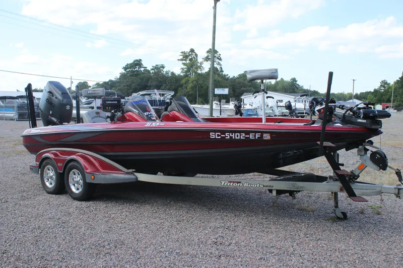 Slide: The Image of 2009 Triton 21X3 Pro DC boat on trailer, parked outdoors, with visible equipment and registration. - 24