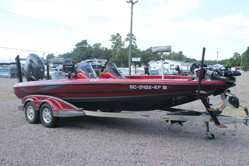 Slide: The Image of 2009 Triton 21X3 Pro DC boat on trailer, red and black, parked outdoors. - 25