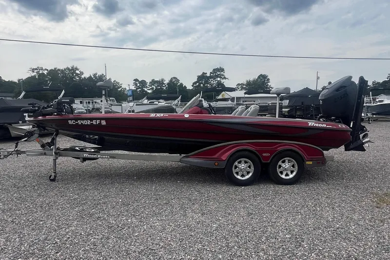 Slide: The Image of 2009 Triton 21X3 Pro DC boat on trailer, parked on gravel lot under cloudy sky. - 6