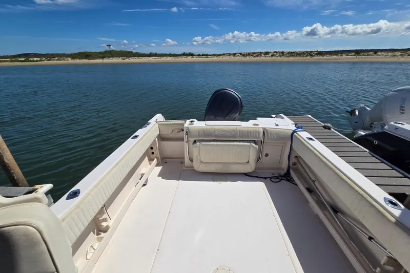 Slide: The Image of 2004 Grady-White Journey 258 boat docked by serene waters under a clear blue sky. - 2