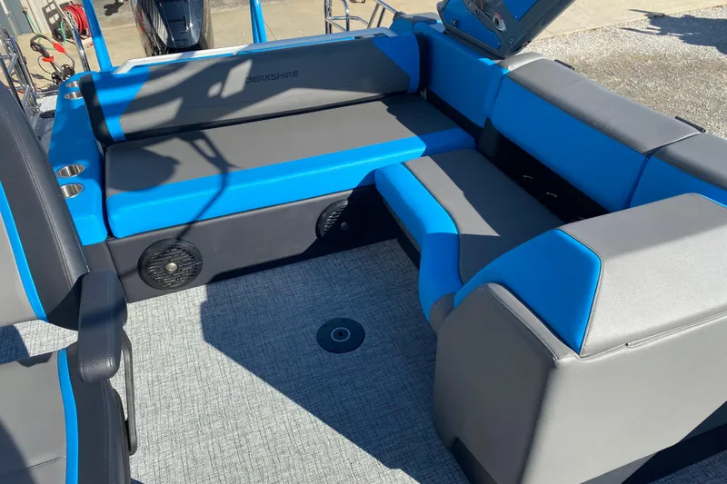 Slide: The Image of 2023 Berkshire 23UL boat interior with blue and gray seating, cup holders, and speakers. - 13