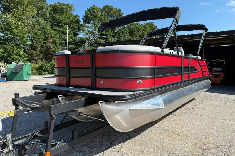 Slide: The Image of 2025 Bentley Pontoons Legacy 243 Swingback, red and black, parked outdoors on a trailer. - 1