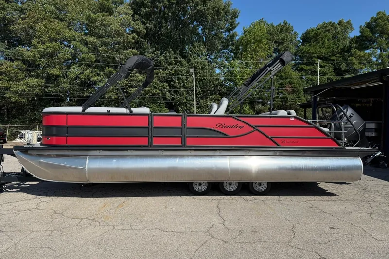 Slide: The Image of 2025 Bentley Pontoons Legacy 243 Swingback, red and black design, parked outdoors. - 2