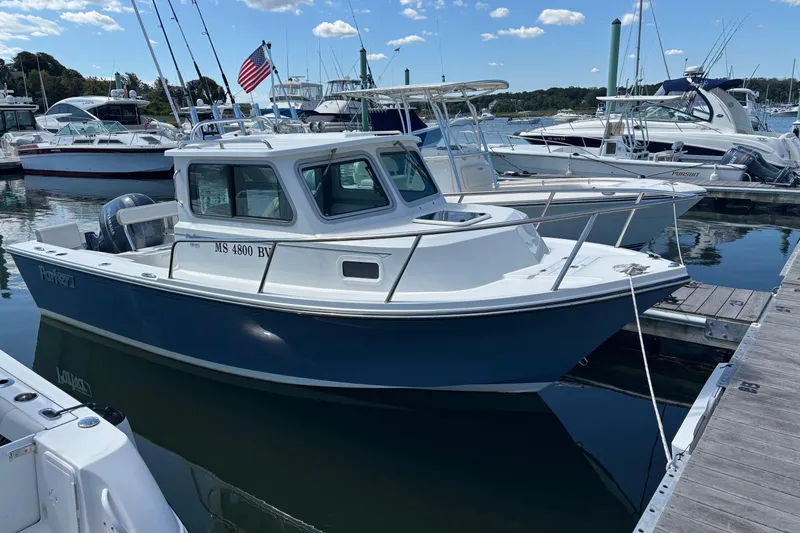 The Image of 2022 Parker 2120 Sport Cabin boat docked in a marina under a clear blue sky. - 0