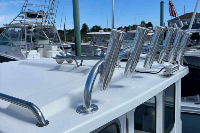 Slide: The Image of 2022 Parker 2120 Sport Cabin boat with rod holders and marina background. - 10