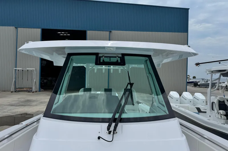 Slide: The Image of 2026 Bertram 34CC boat with windshield and wiper, docked near a warehouse. - 17