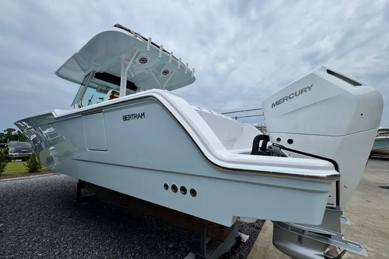 Slide: The Image of 2026 Bertram 34CC boat with Mercury engine, displayed outdoors on gravel. - 6