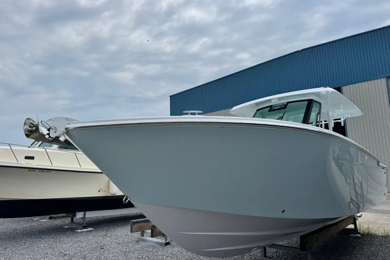 Slide: The Image of 2026 Bertram 34CC boat displayed outdoors near a blue warehouse. - 7