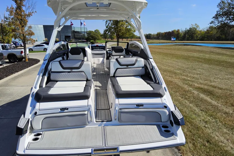 Slide: The Image of 2023 Yamaha Boats 275SDX with luxurious seating, parked outdoors on a sunny day. - 23