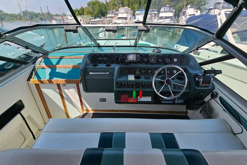 Slide: The Image of 1989 Sea Ray 280 Sundancer cockpit with steering wheel, gauges, and seating in a marina setting. - 10