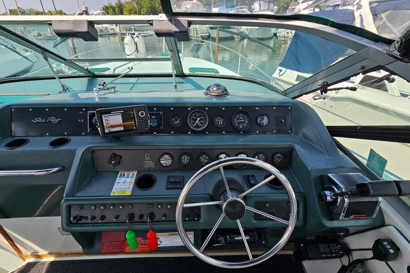 Slide: The Image of 1989 Sea Ray 280 Sundancer helm with gauges, steering wheel, and navigation equipment. - 11