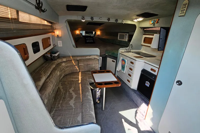 Slide: The Image of Interior of a 1989 Sea Ray 280 Sundancer boat with cozy seating and kitchenette. - 12