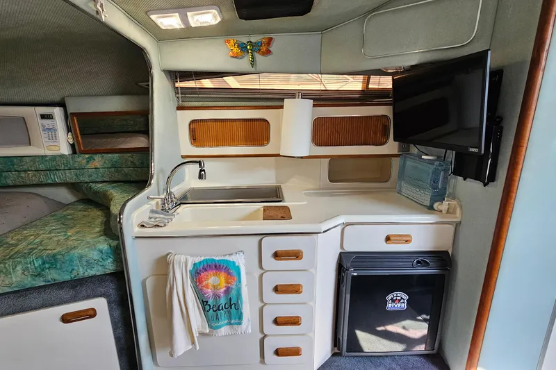 Slide: The Image of 1989 Sea Ray 280 Sundancer cabin interior with kitchenette, sink, and TV. - 17