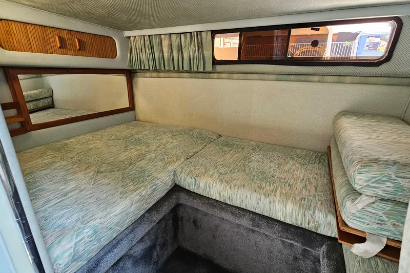 Slide: The Image of Cozy cabin interior of 1989 Sea Ray 280 Sundancer with cushioned seating and window. - 19