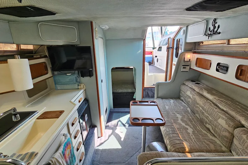 Slide: The Image of Interior of 1989 Sea Ray 280 Sundancer boat with kitchenette and seating area. - 21