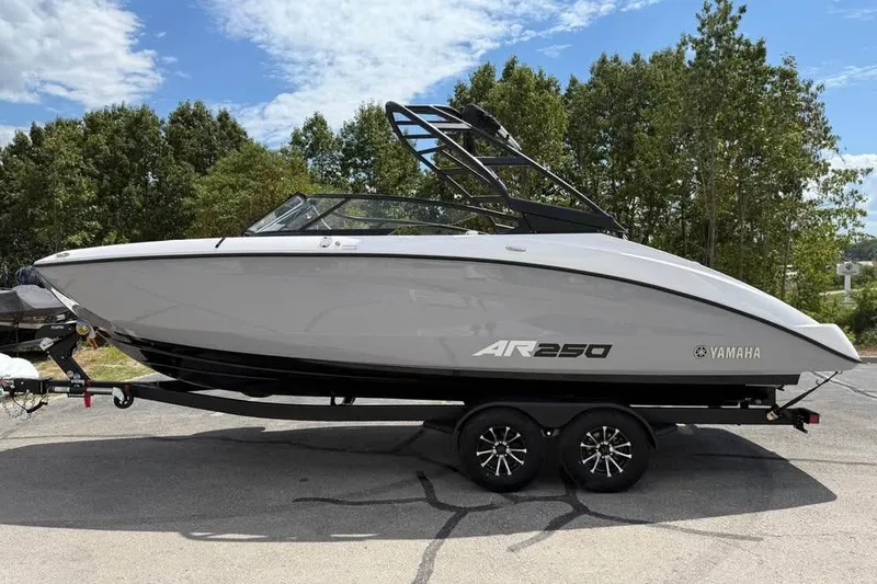 The Image of 2026 Yamaha Boats AR250 on trailer, sleek design, parked outdoors under blue sky. - 0