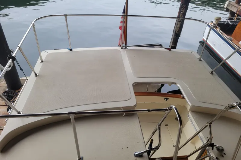 Slide: The Image of 1981 Bayliner 3270 Explorer boat deck with railing, docked by calm water. - 10