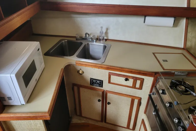 Slide: The Image of 1981 Bayliner 3270 Explorer kitchen with microwave, double sink, and stove. - 16