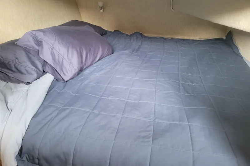 Slide: The Image of Cozy bed with blue bedding inside 1981 Bayliner 3270 Explorer boat cabin. - 23