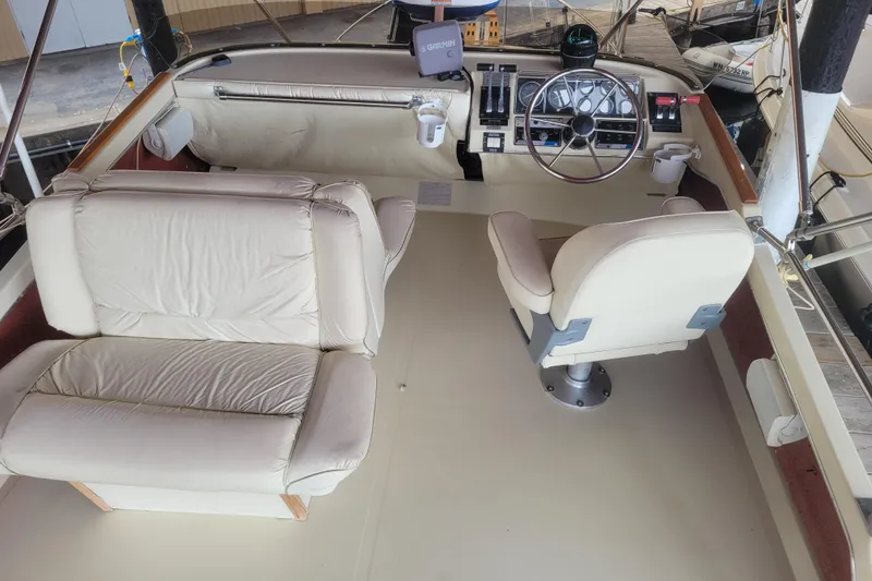 Slide: The Image of 1981 Bayliner 3270 Explorer helm with beige seating and steering wheel in a marina setting. - 7