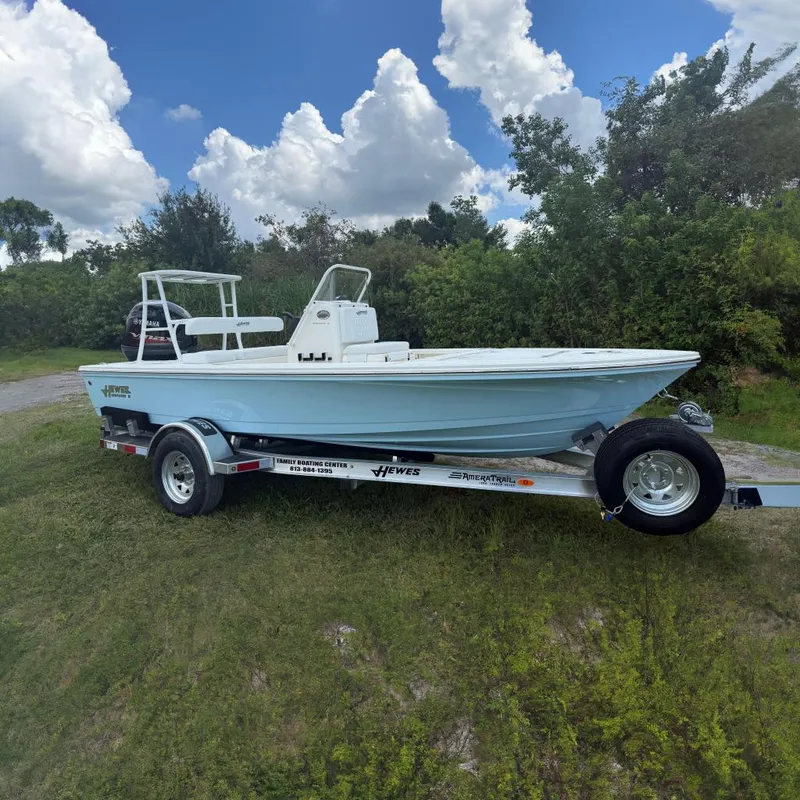 The Image of 2026 Hewes 16 Redfisher boat on trailer, parked outdoors with lush greenery background. - 0