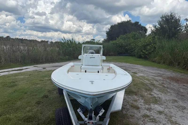Slide: The Image of 2026 Hewes 16 Redfisher boat on trailer, parked on grassy area under cloudy sky. - 11