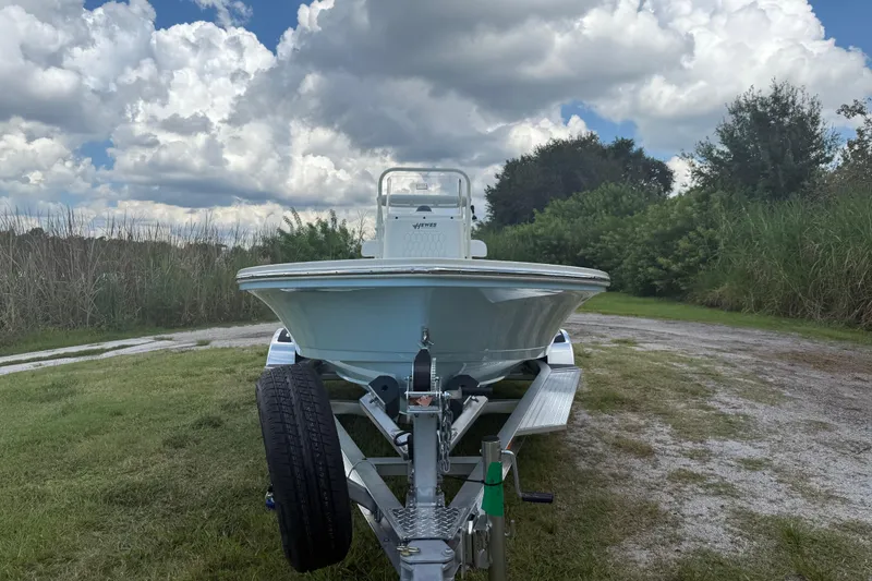 Slide: The Image of 2026 Hewes 16 Redfisher boat on trailer, parked on grassy path under cloudy sky. - 12