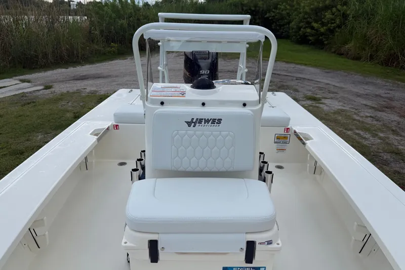 Slide: The Image of 2026 Hewes 16 Redfisher boat interior with seating and console, parked on grassy area. - 19
