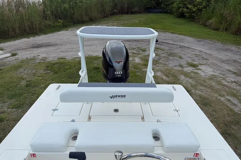 Slide: The Image of 2026 Hewes 16 Redfisher boat with Yamaha 90 engine, parked on grassy area. - 20