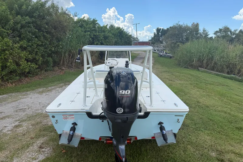 Slide: The Image of 2026 Hewes 16 Redfisher boat with Yamaha 90 engine, parked on grassy area. - 7