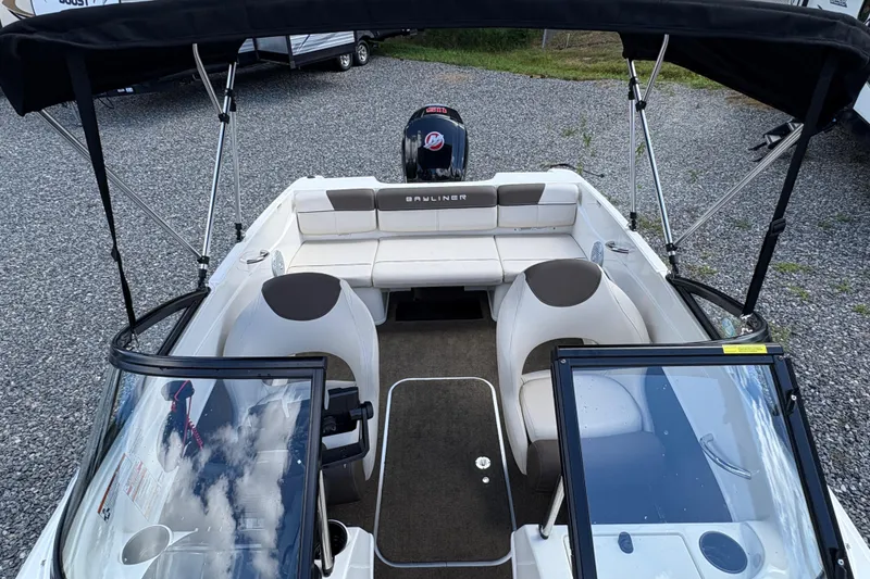 Slide: The Image of 2020 Bayliner 170 Bowrider boat interior with seating and steering wheel, parked on gravel. - 20